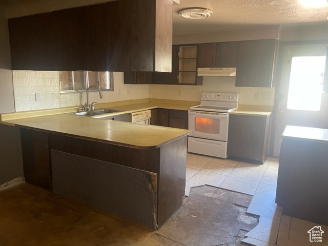 Kitchen featuring light tile flooring, kitchen peninsula, dark brown cabinets, white range with electric cooktop, and sink