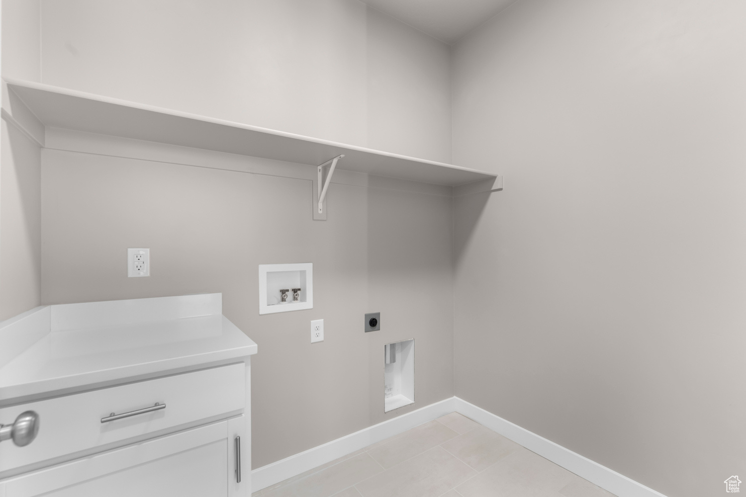 Clothes washing area with hookup for an electric dryer, light tile flooring, and washer hookup