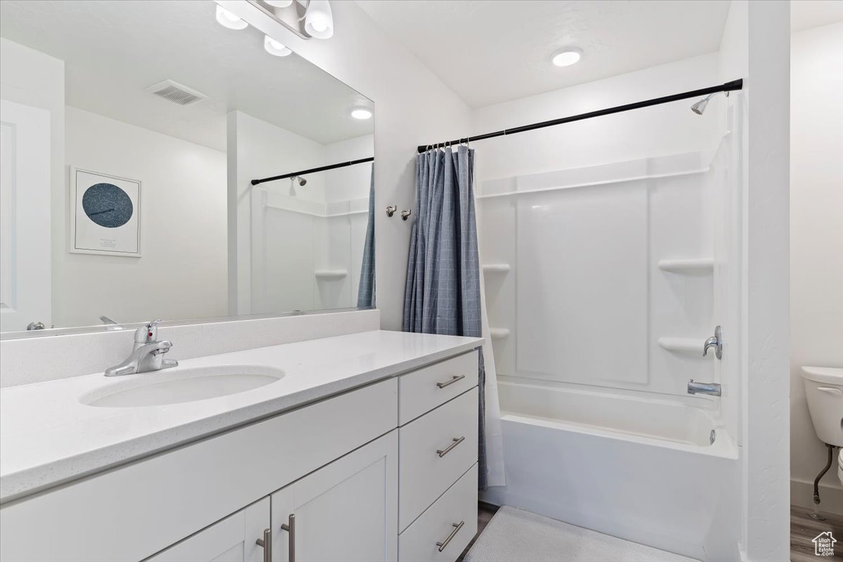 Full bathroom featuring shower / bath combo with shower curtain, toilet, and vanity with extensive cabinet space