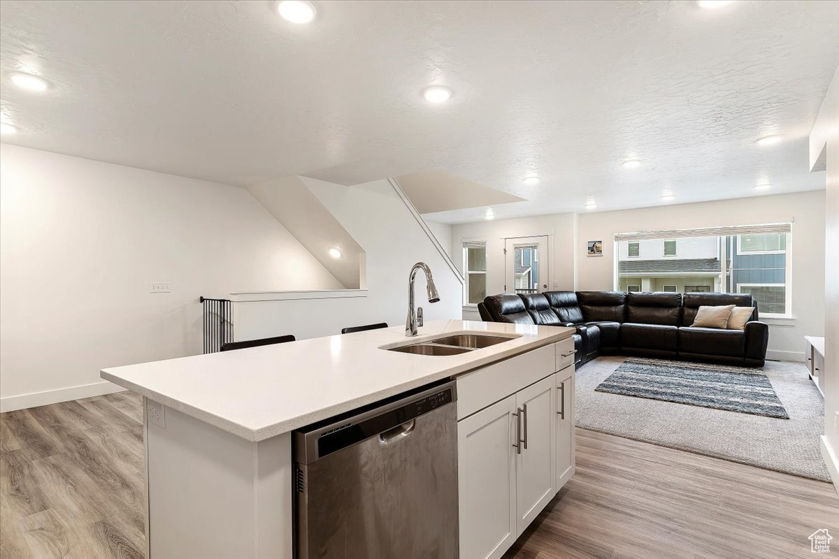 Kitchen featuring sink, a kitchen island with sink, stainless steel dishwasher, and light hardwood / wood-style flooring