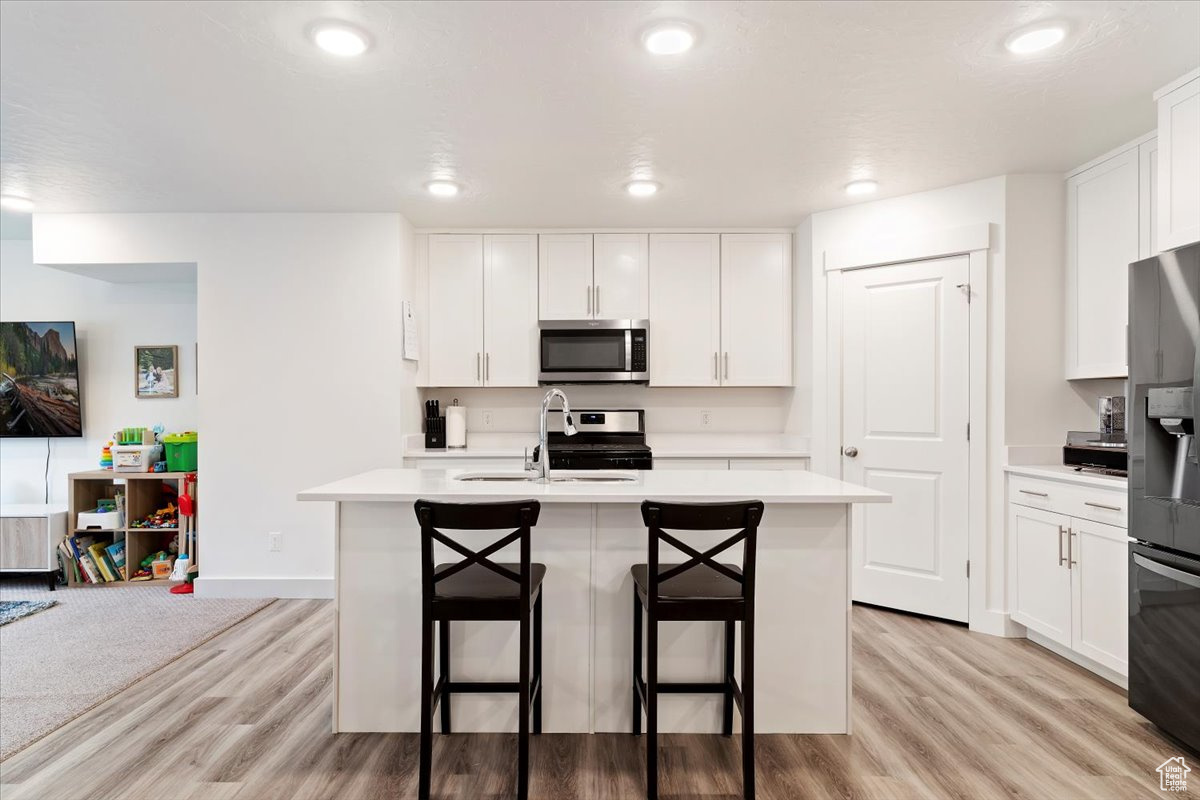 Kitchen featuring appliances with stainless steel finishes, white cabinets, and light wood-type flooring