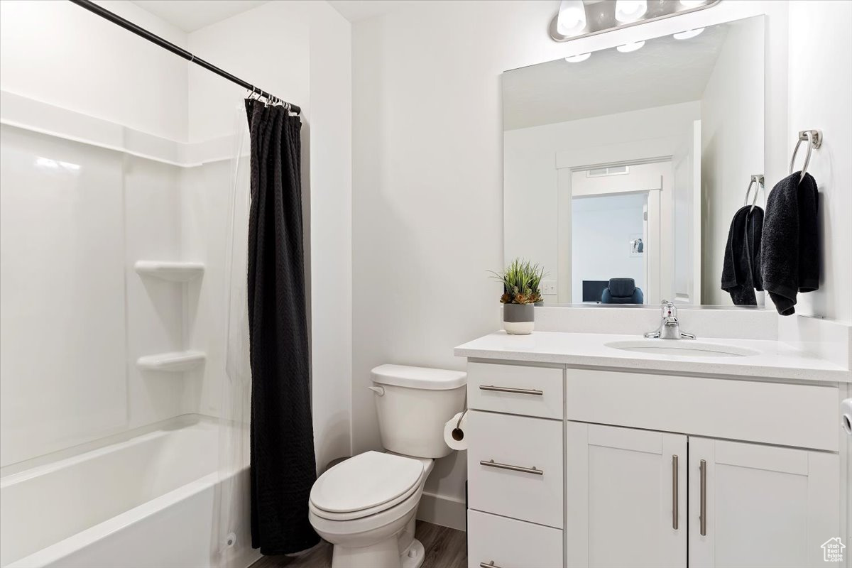 Full bathroom with shower / bath combo, wood-type flooring, toilet, and vanity with extensive cabinet space