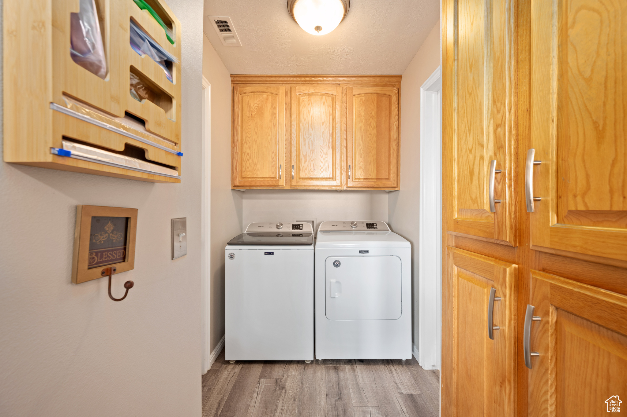 Laundry area featuring independent washer and dryer, wood-type flooring, and cabinets