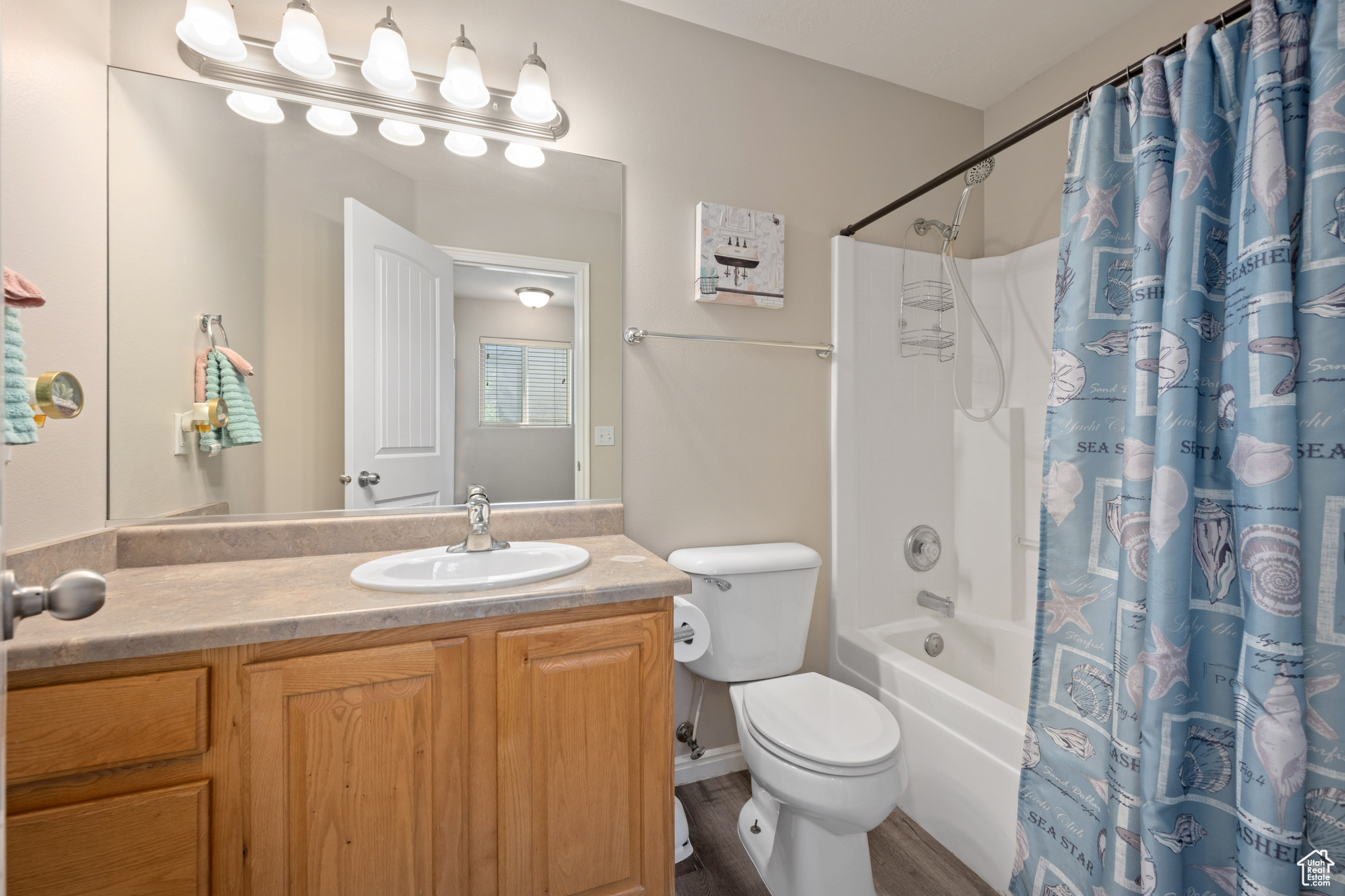 Full bathroom featuring shower / bathtub combination with curtain, hardwood / wood-style flooring, toilet, and large vanity