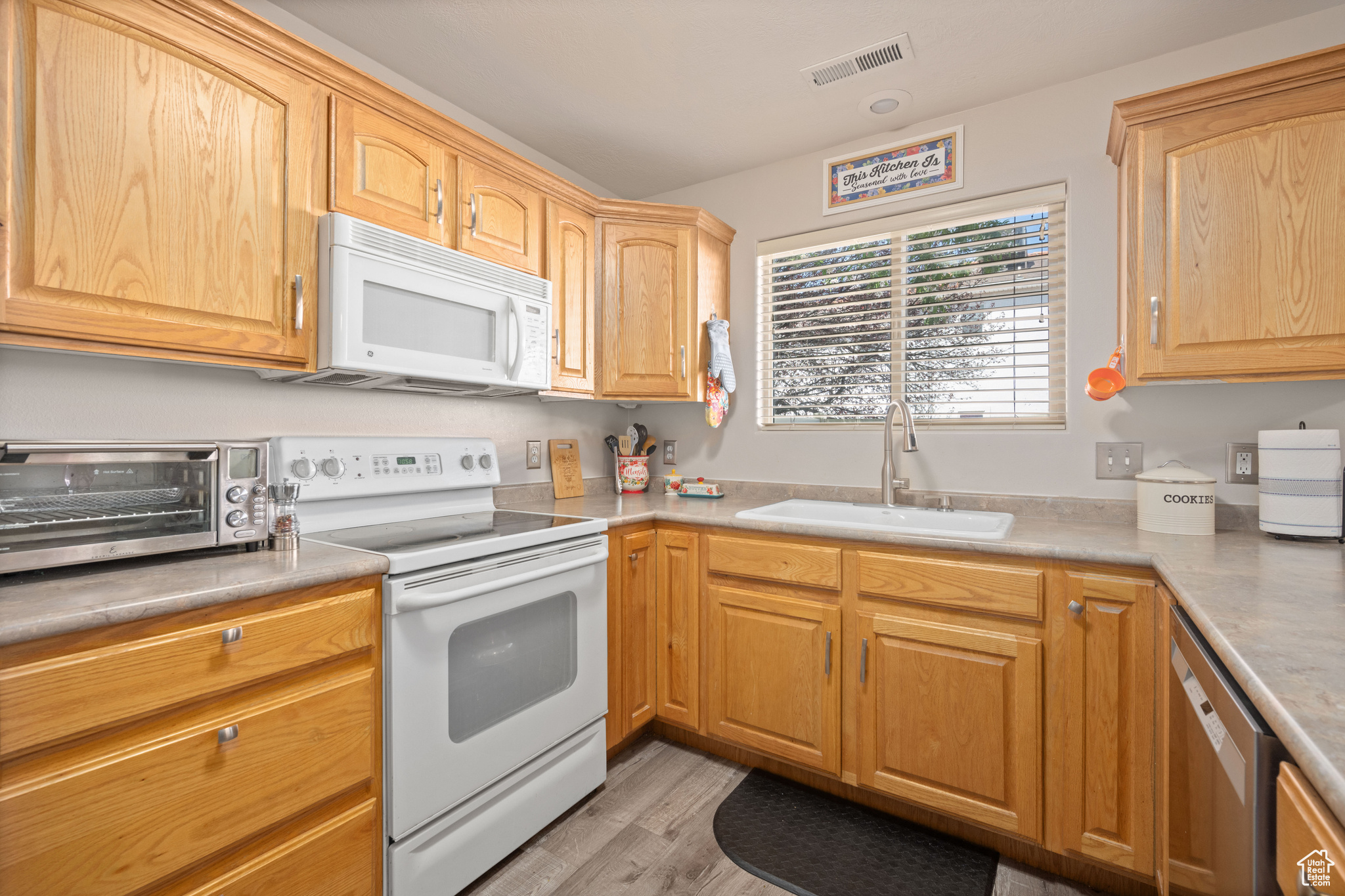 Kitchen featuring sink, white appliances, and light hardwood / wood-style flooring