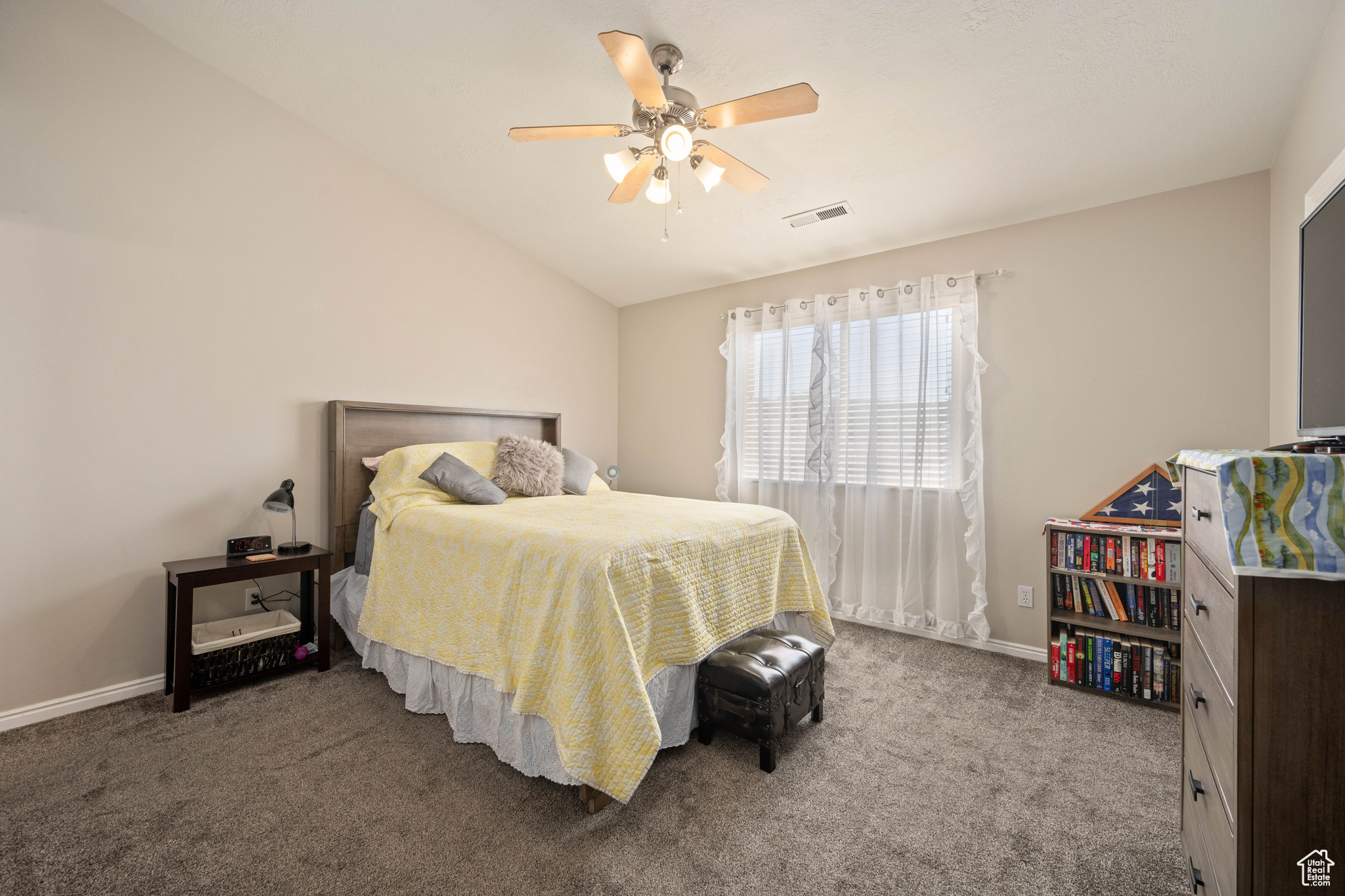 Carpeted bedroom with ceiling fan and vaulted ceiling