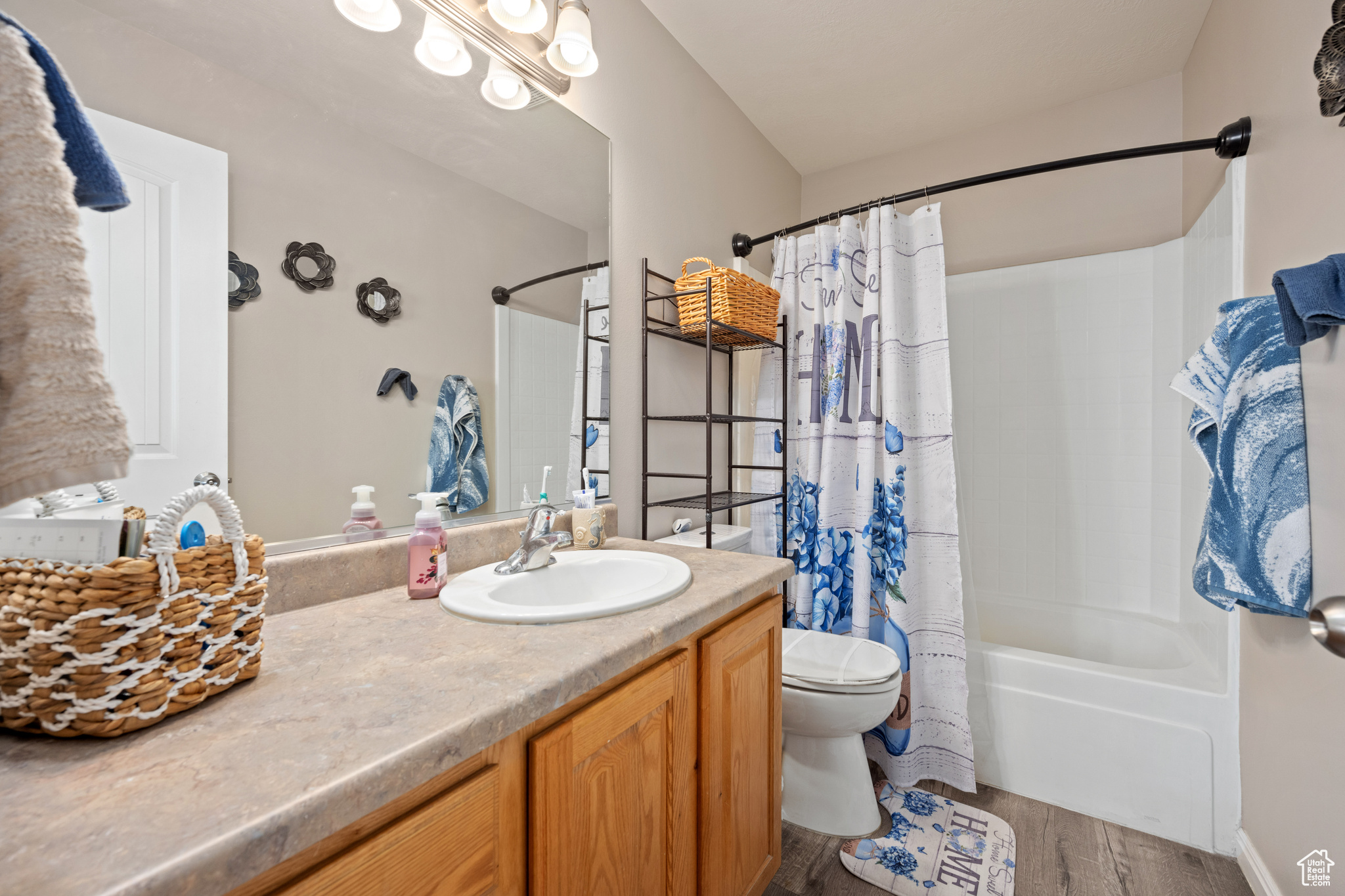 Full bathroom with shower / bath combo with shower curtain, vanity, toilet, and hardwood / wood-style floors