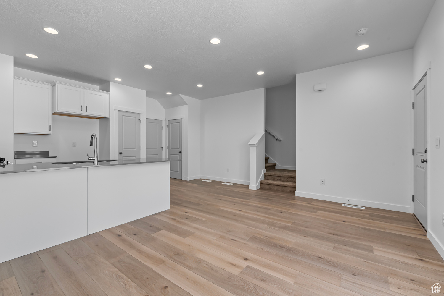 Kitchen with sink, light hardwood / wood-style flooring, and white cabinets