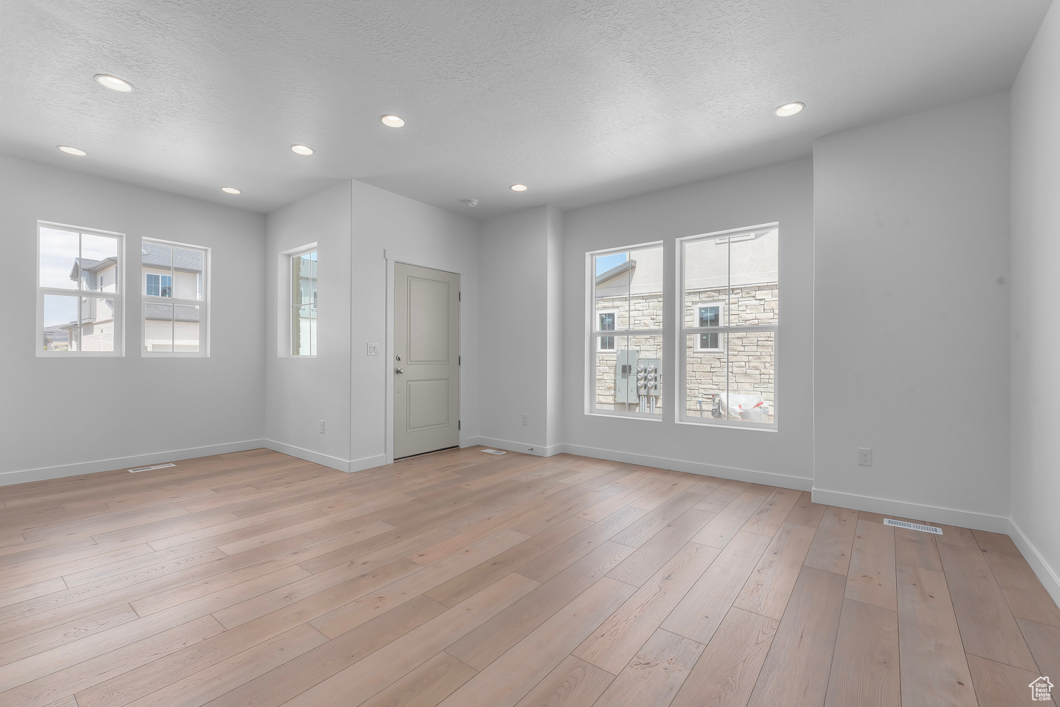 Unfurnished room featuring light hardwood / wood-style floors and a textured ceiling