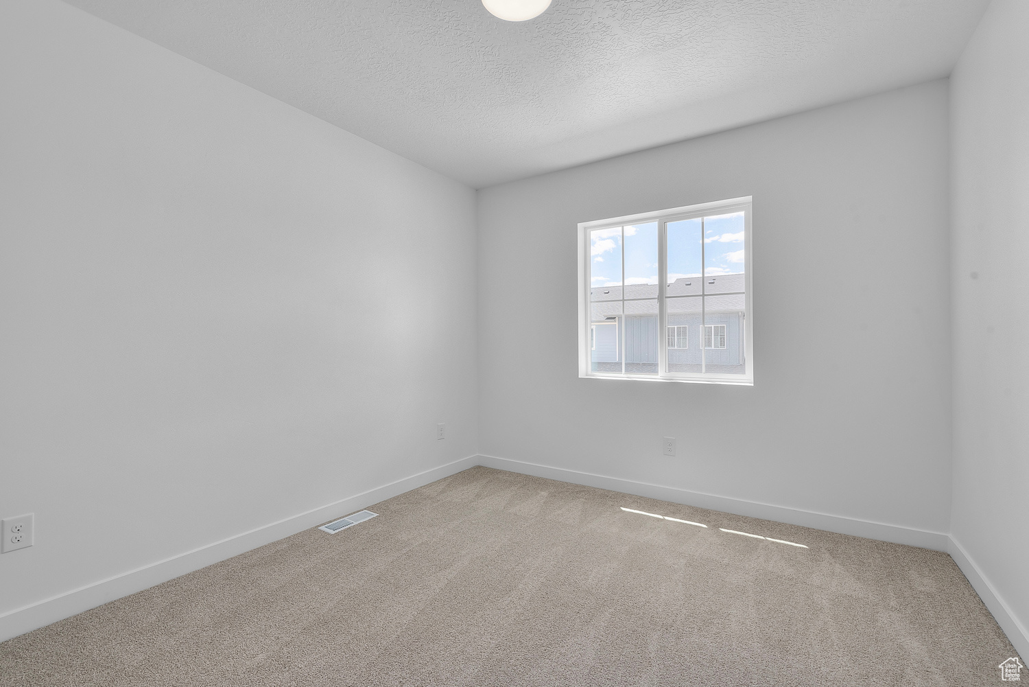 Carpeted spare room featuring a textured ceiling