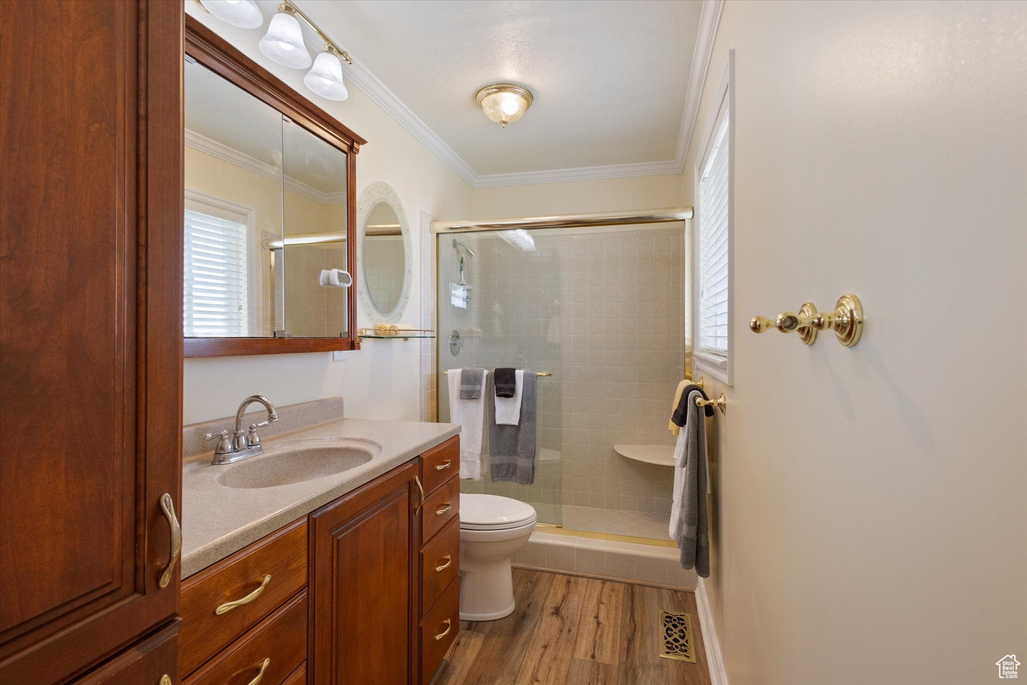 Bathroom featuring toilet, crown molding, a shower with door, wood-type flooring, and vanity