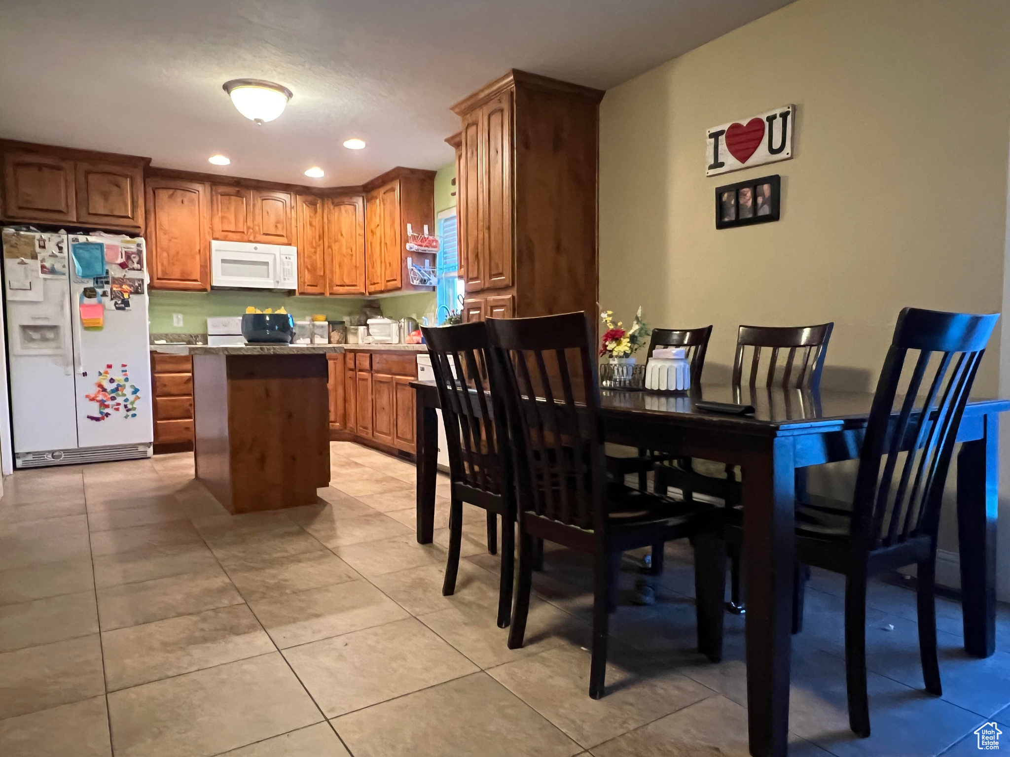 Kitchen featuring a center island, white appliances, and light tile flooring