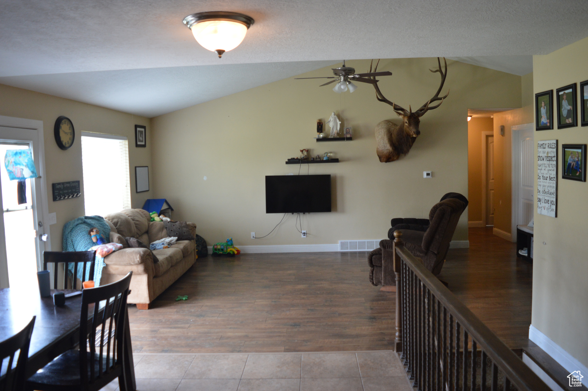 Tiled living room with ceiling fan and lofted ceiling