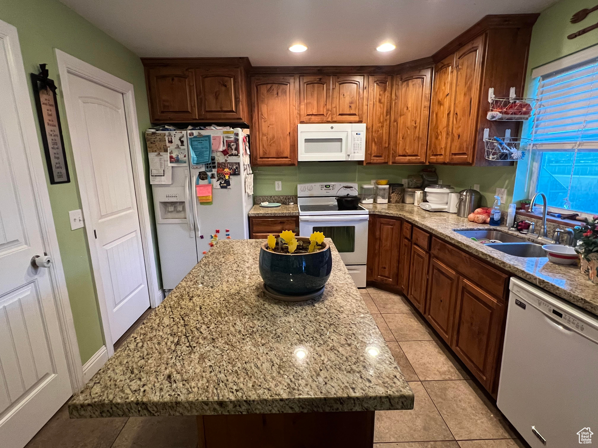 Kitchen featuring sink, a center island, white appliances, and light tile floors