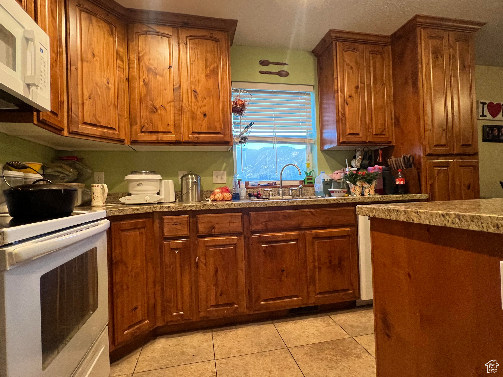 Kitchen featuring white appliances, sink, and light tile flooring