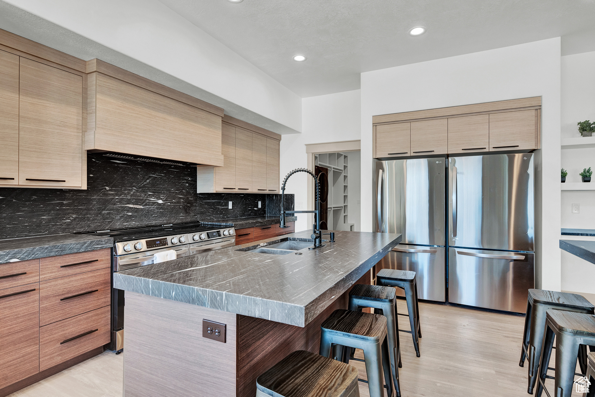 Kitchen featuring stainless steel appliances, a kitchen breakfast bar, tasteful backsplash, a kitchen island with sink, and sink