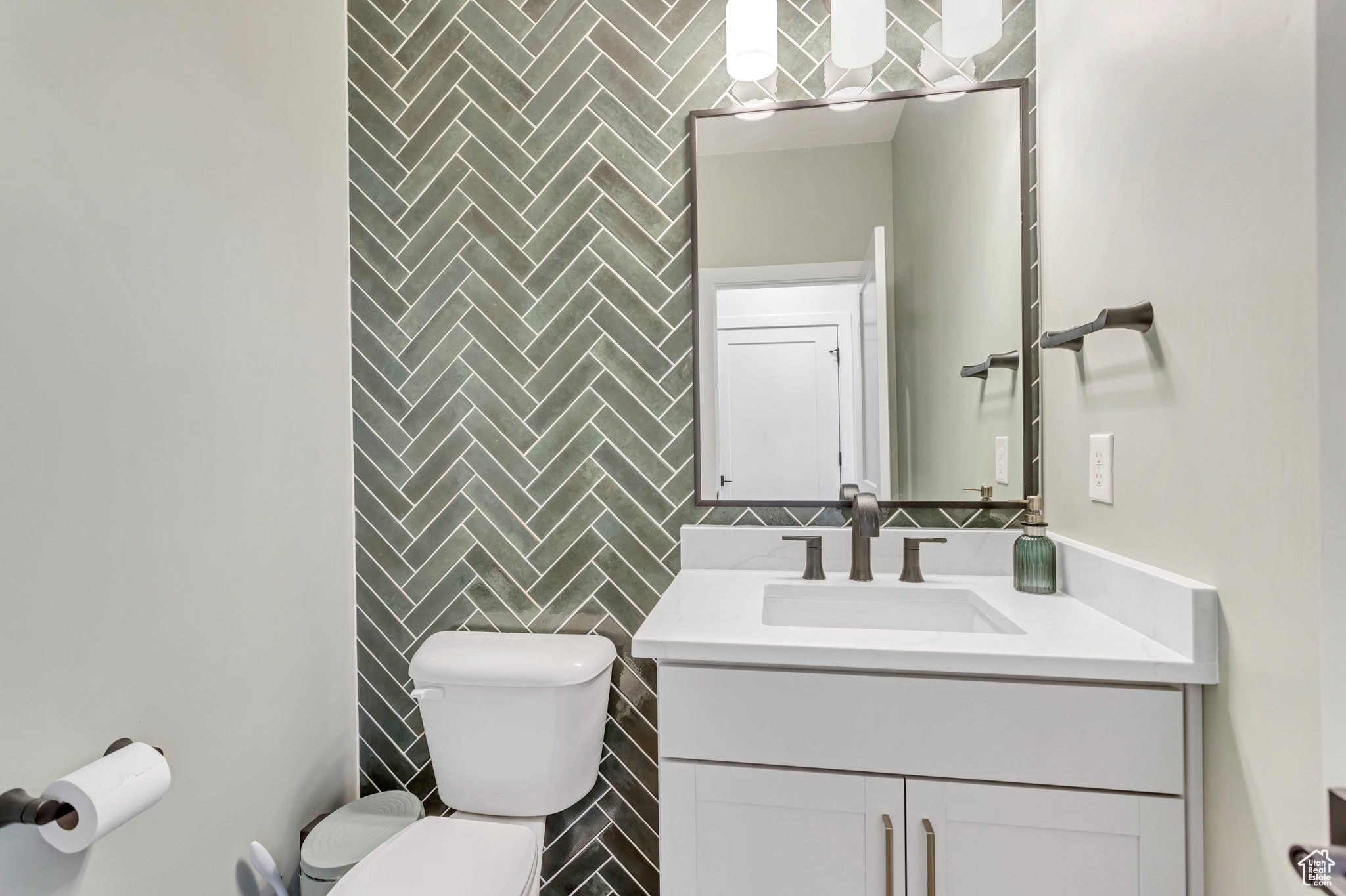 Half bath featuring tile backsplash, toilet, and large vanity