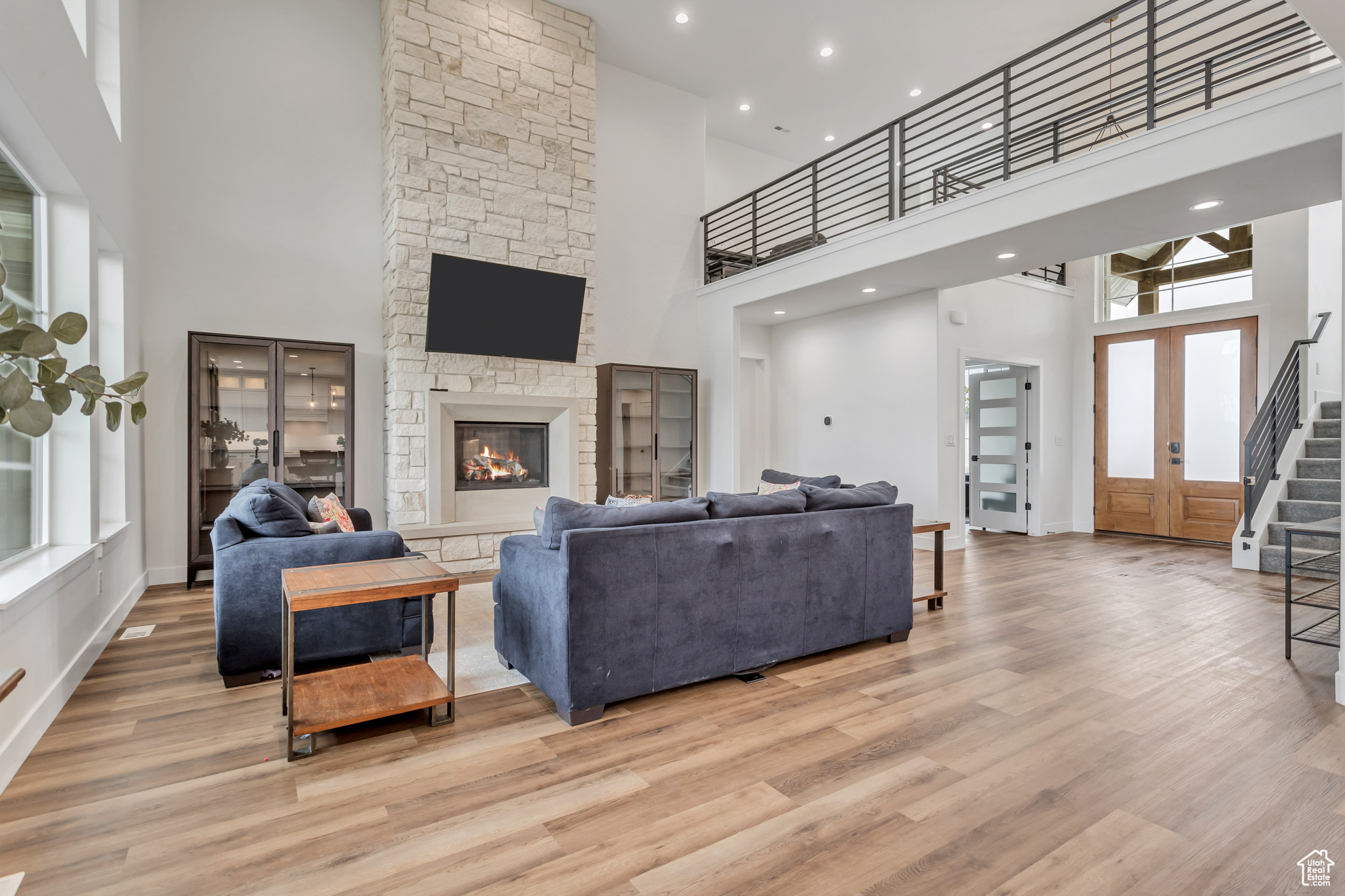 Living room featuring a high ceiling, hardwood / wood-style floors, entry French doors, and a beautiful custom  stone surround fireplace