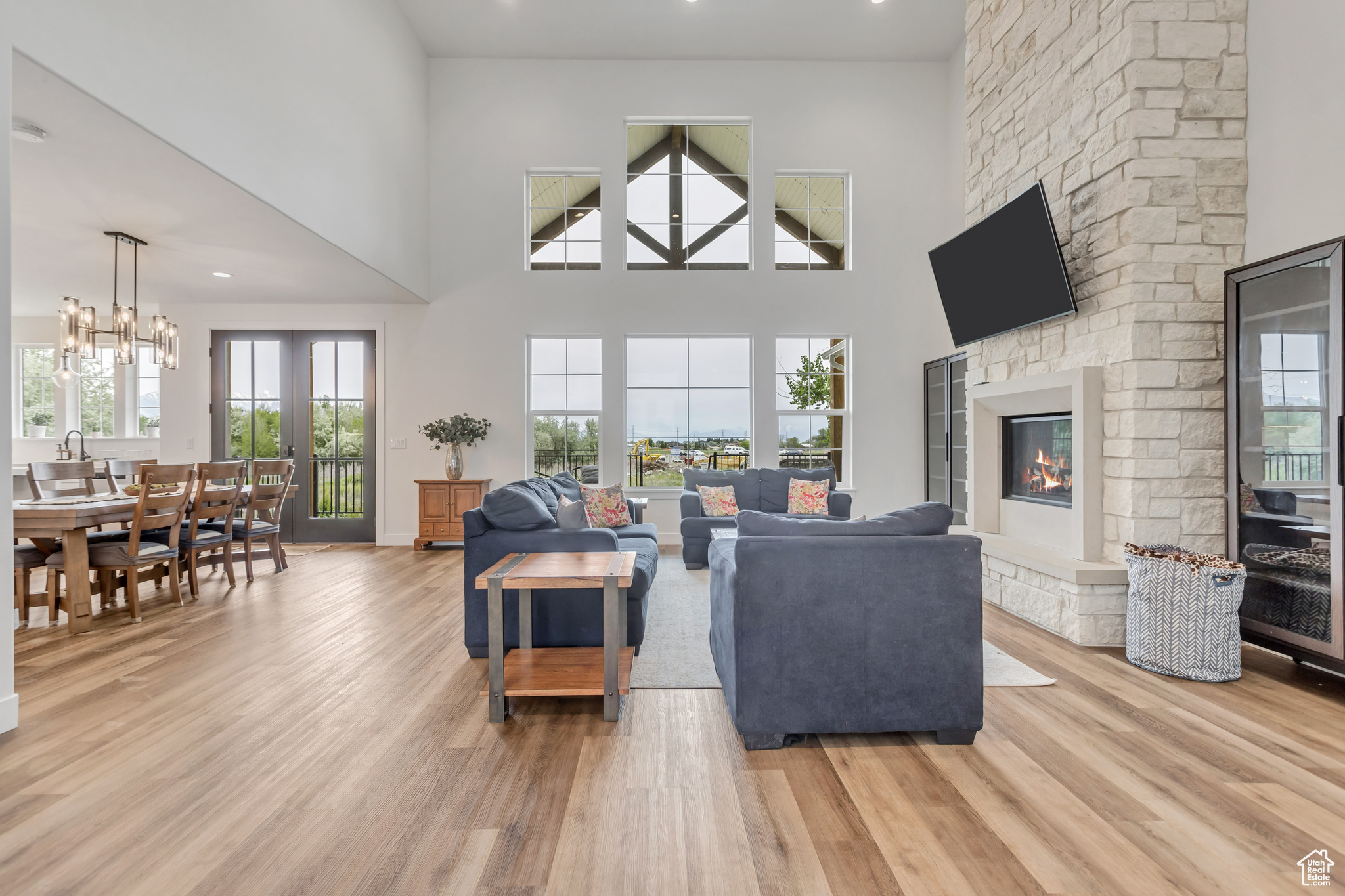 Living room featuring a custom, stone surround fireplace, French doors to outside deck, a towering ceiling