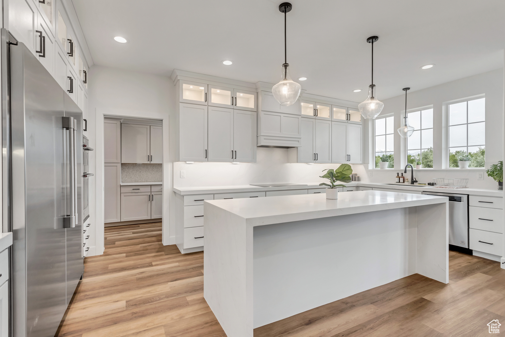 Kitchen with a large center island, white cabinetry, Butlers Pantry entry to the left, hanging light fixtures and stainless steel appliances