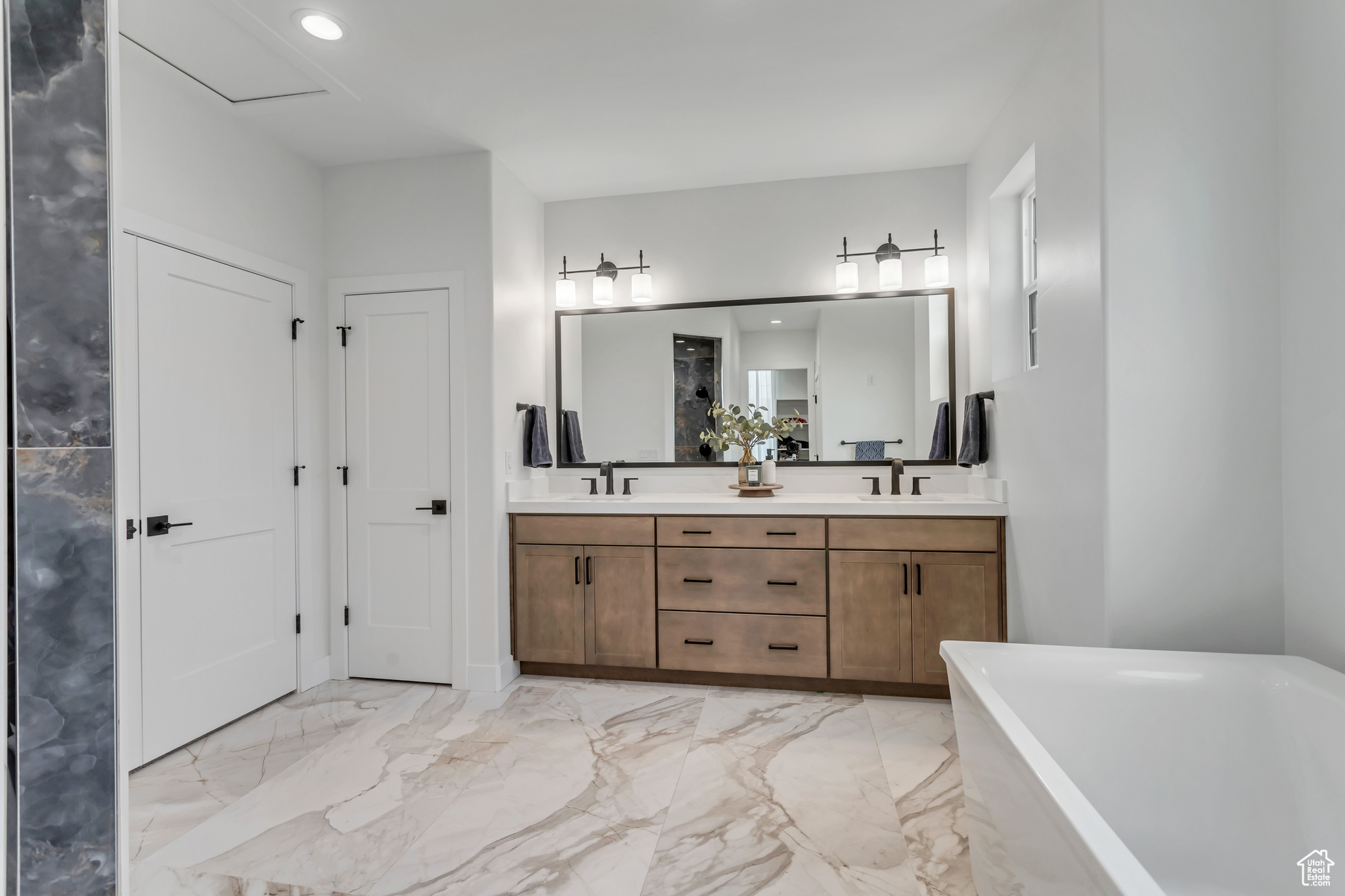 Spacious primary bathroom featuring double vanity, tile flooring, and a large soaking tub