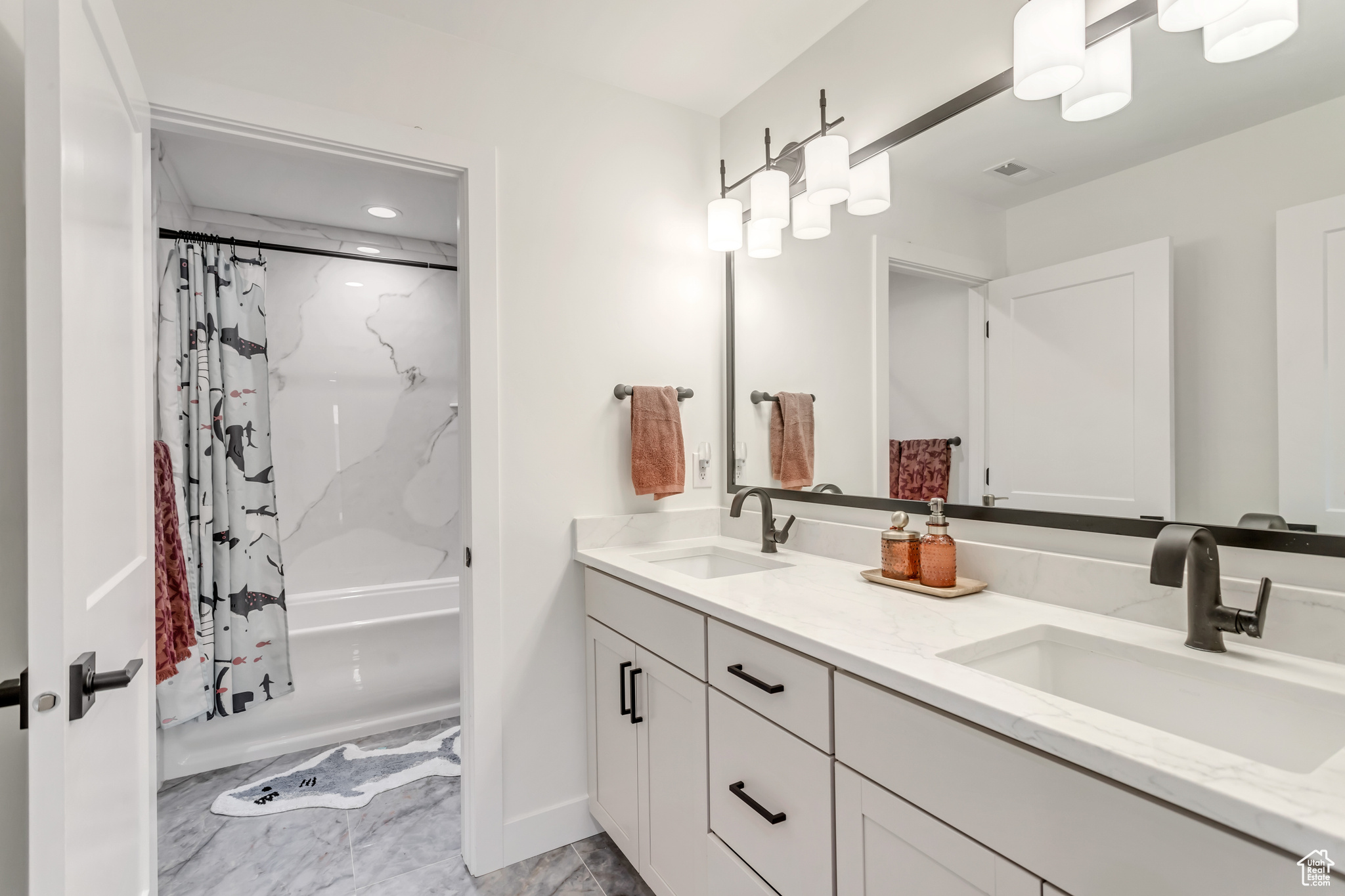 Bathroom with tile floors, double sink vanity, and shower / tub combo