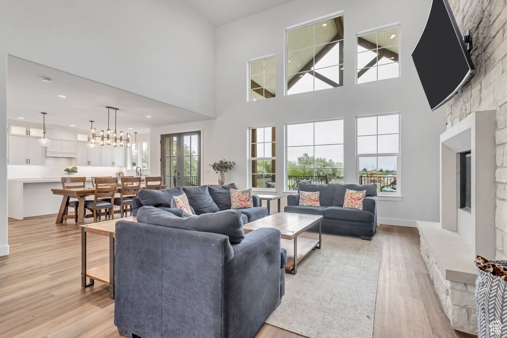 Living room featuring a high ceiling, plenty of natural light, custom surround stone fireplace