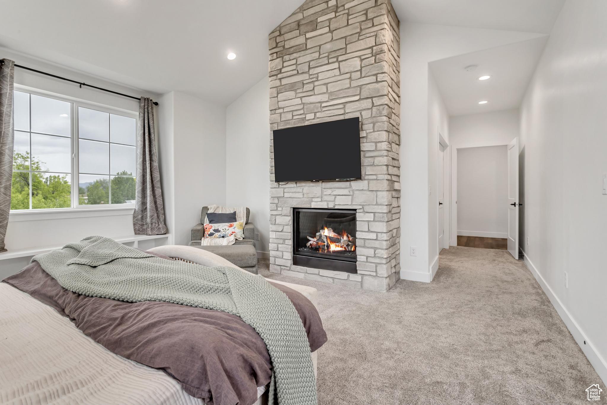 Primary bedroom with vaulted ceiling & a stone fireplace