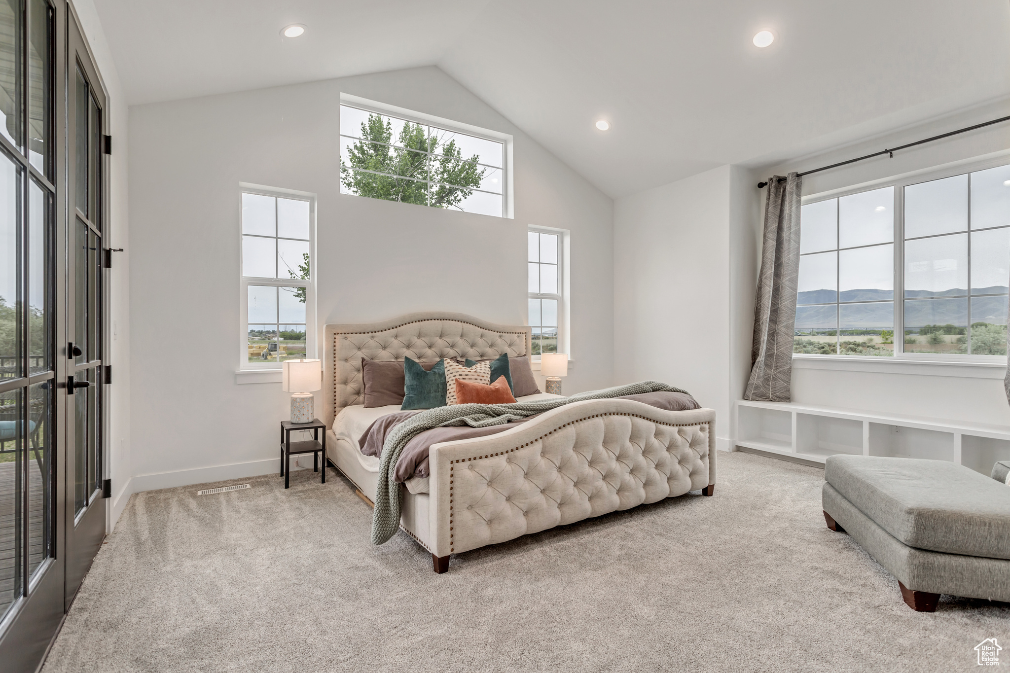 Primary bedroom featuring high vaulted ceiling, window seat, fireplace with a mountain view, French doors leading out to the spacious Trex deck