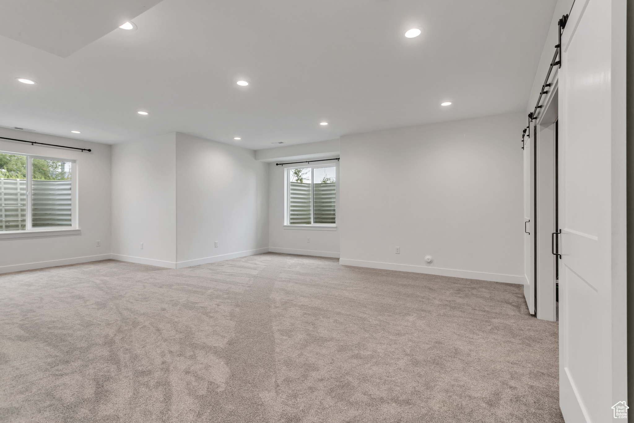 Basement carpeted family/rec room with a barn door on the right leading into the theater room and light colored carpet with 9' ceilings