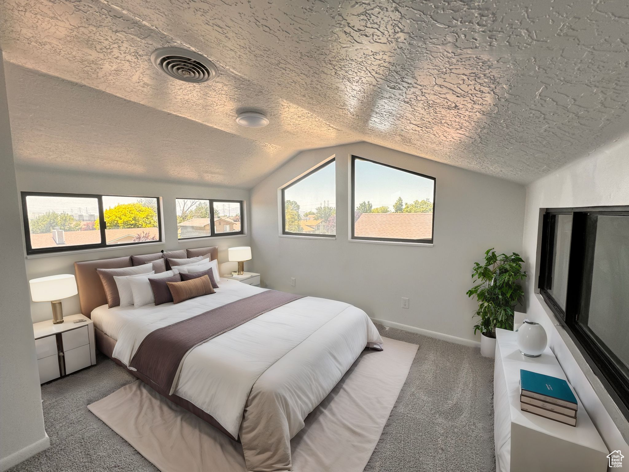 Bedroom with vaulted ceiling, carpet, and a textured ceiling