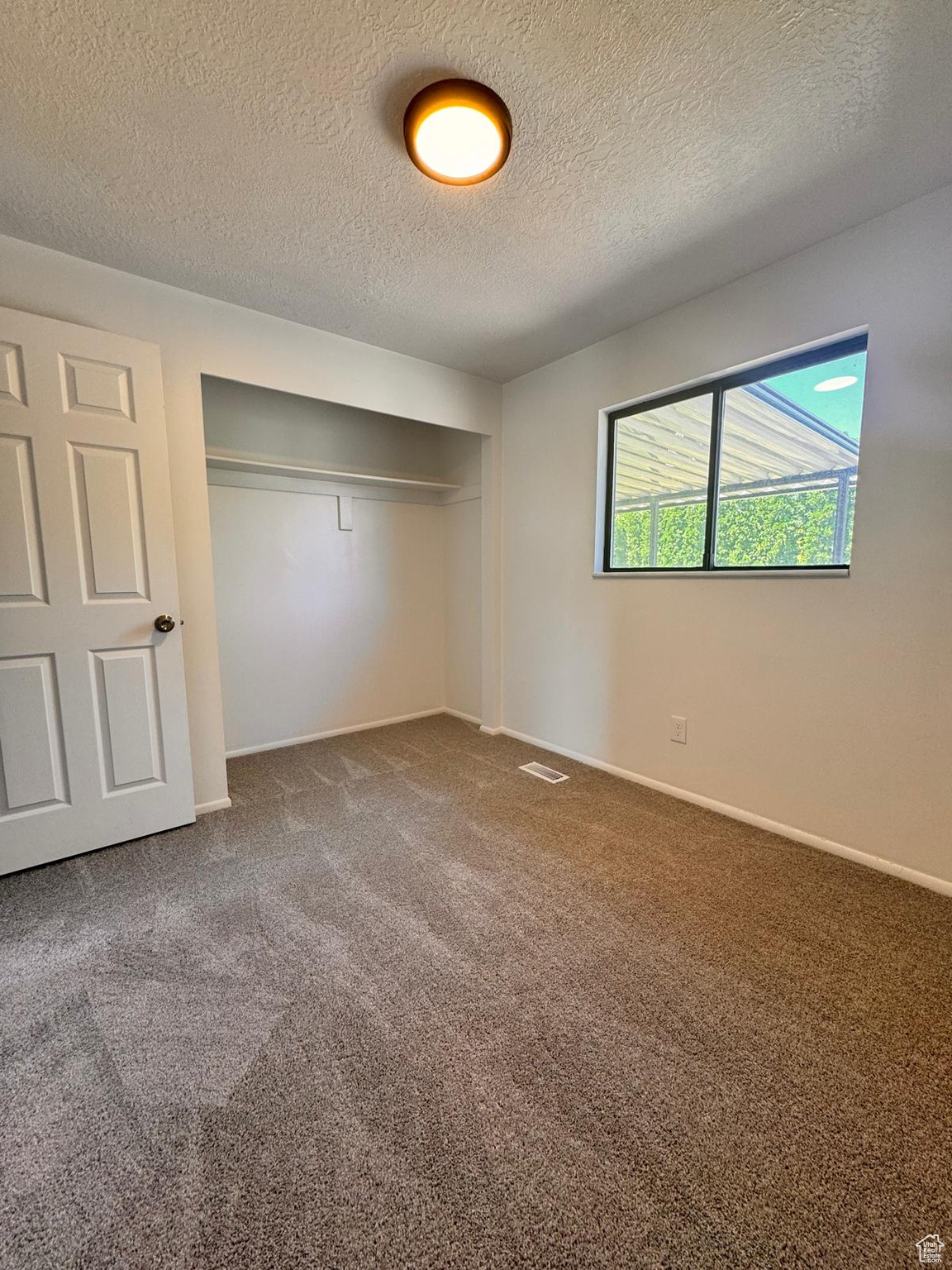 Unfurnished bedroom featuring a closet, a textured ceiling, and carpet floors
