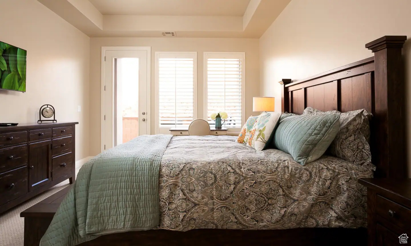 Bedroom with a raised ceiling and carpet floors