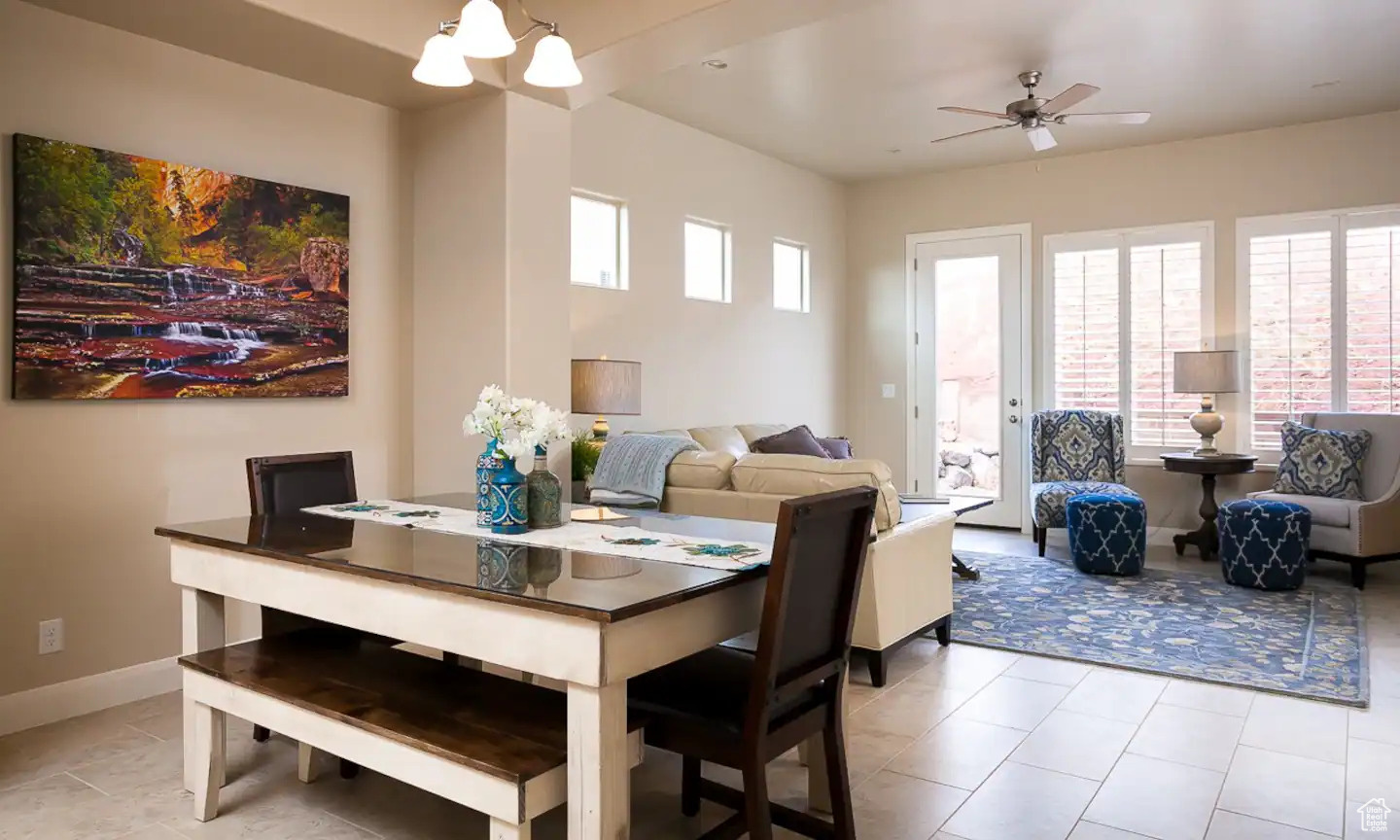 Tiled dining space featuring ceiling fan with notable chandelier