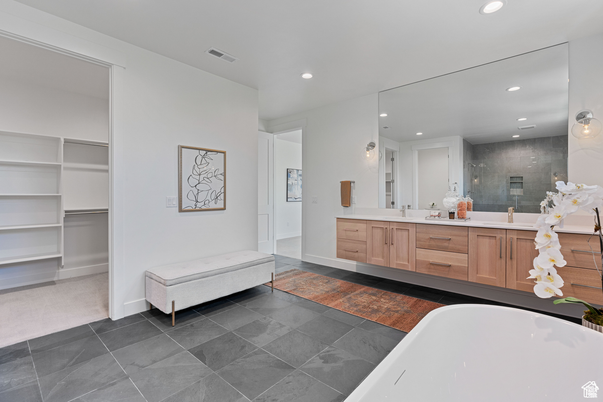 Primary Bathroom featuring tile flooring, a washtub, dual sinks, and vanity with extensive cabinet space