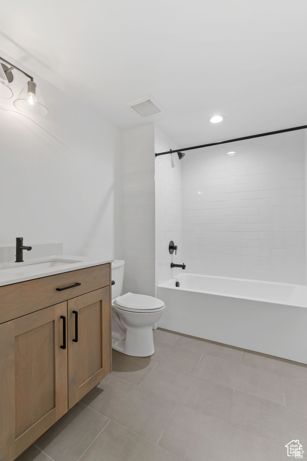 Basement Full bathroom with tile floors, vanity, toilet, and tiled shower / bath combo