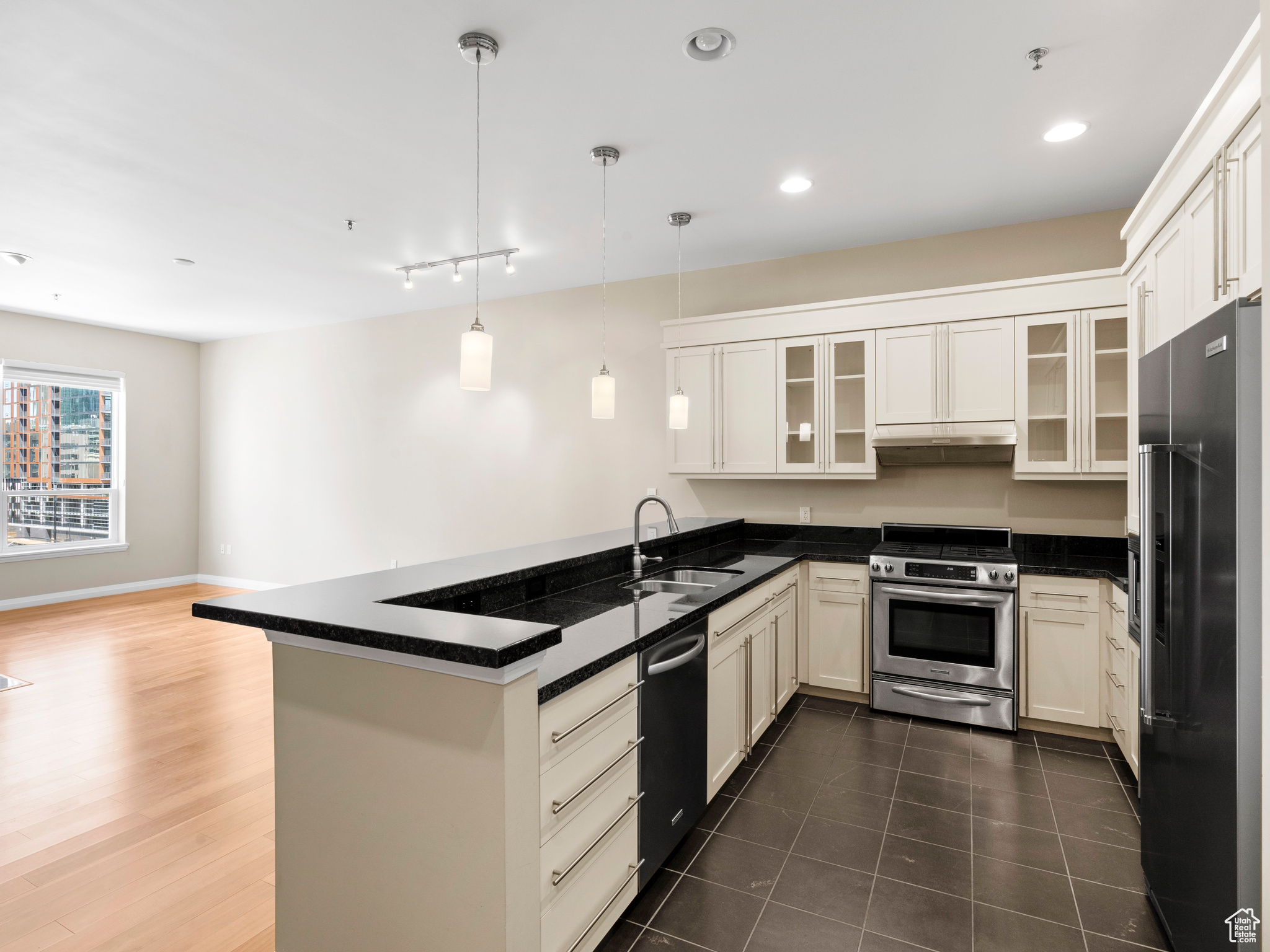 Kitchen featuring hanging light fixtures, dark hardwood / wood-style floors, kitchen peninsula, high end appliances, and sink