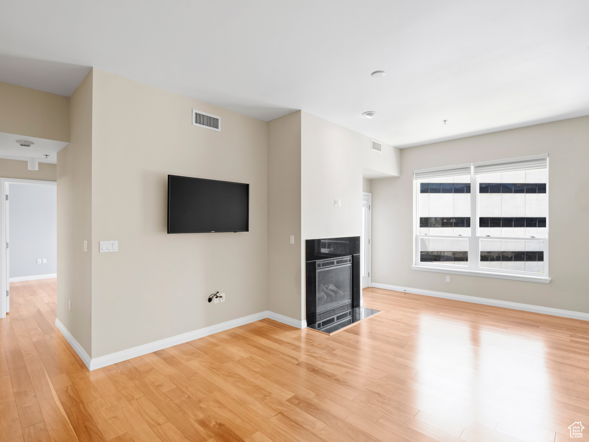 Unfurnished living room featuring a high end fireplace and light wood-type flooring