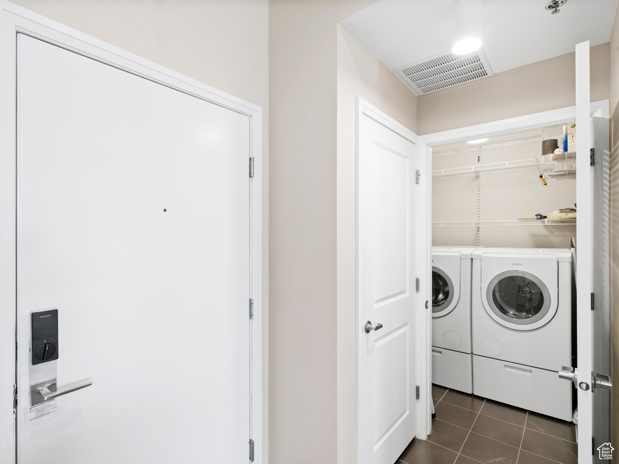 Laundry room with separate washer and dryer and dark tile floors