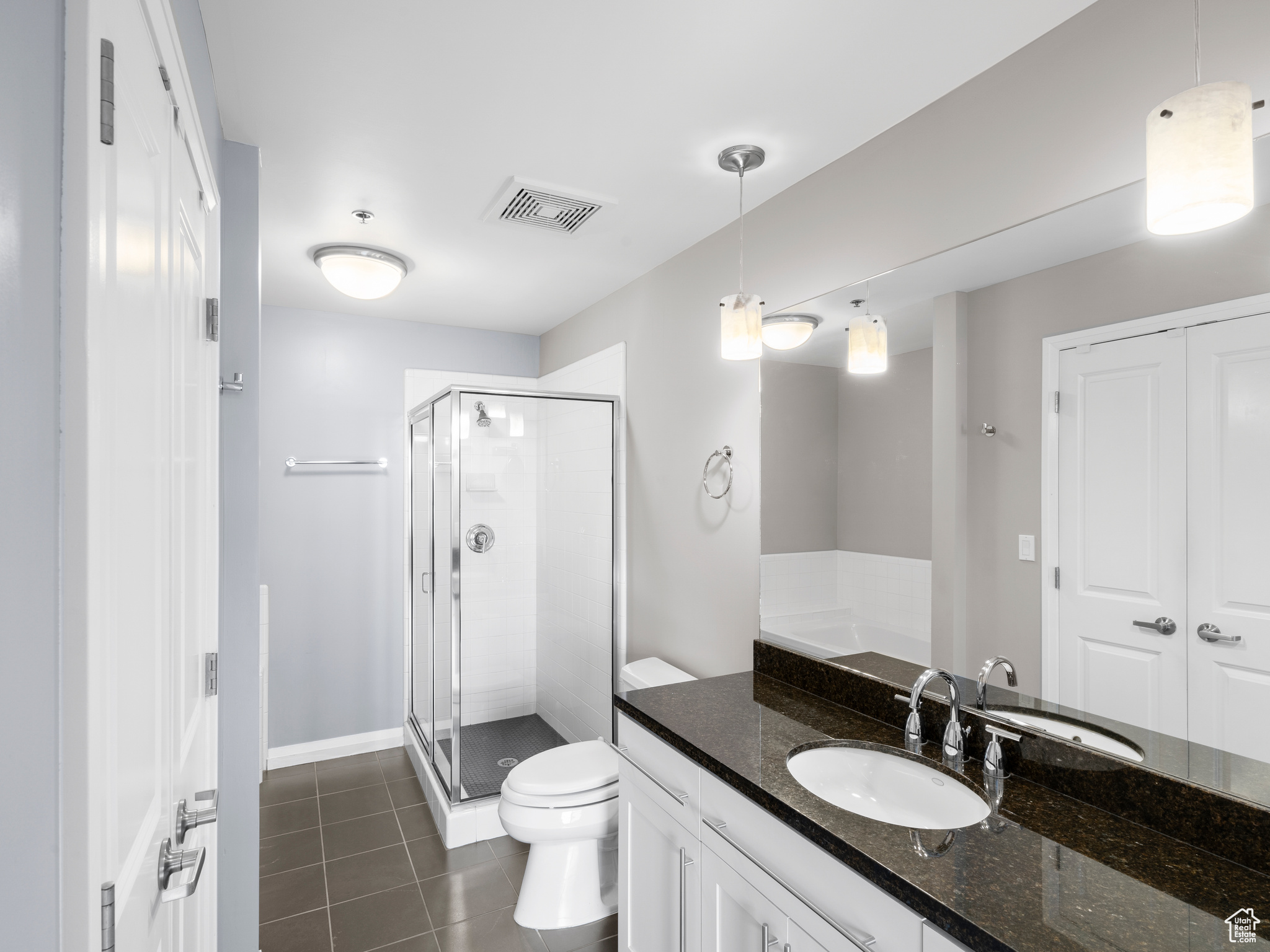 Bathroom featuring tile flooring, oversized vanity, an enclosed shower, and toilet