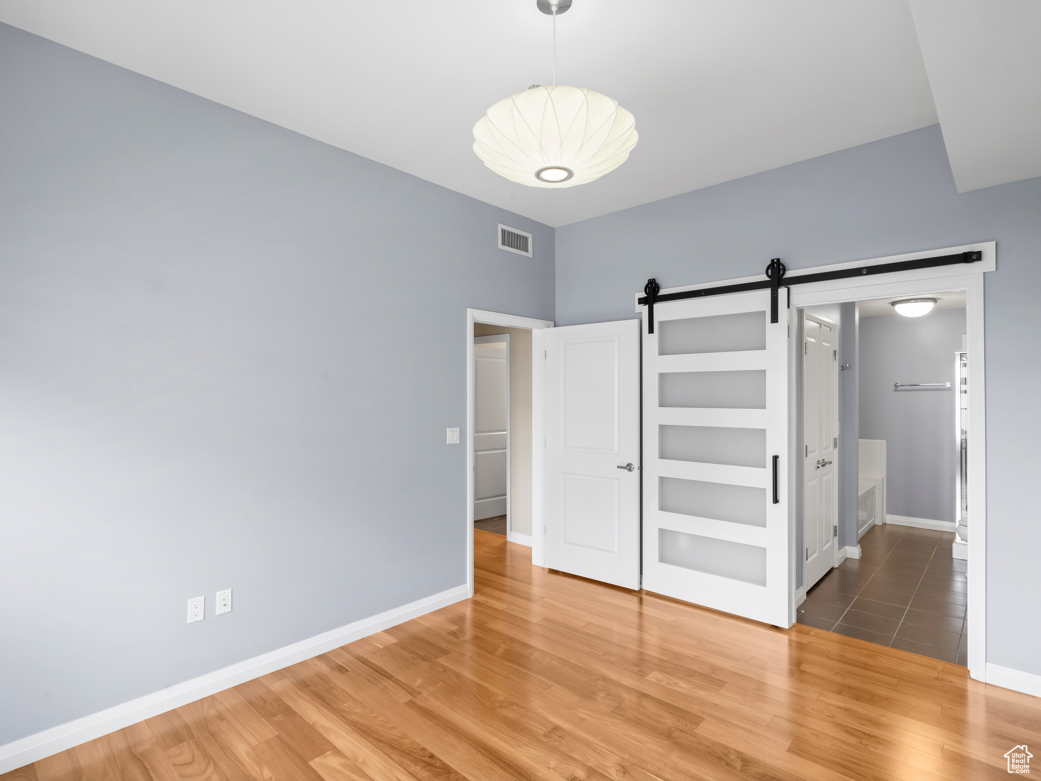 Unfurnished bedroom featuring a barn door and hardwood / wood-style floors