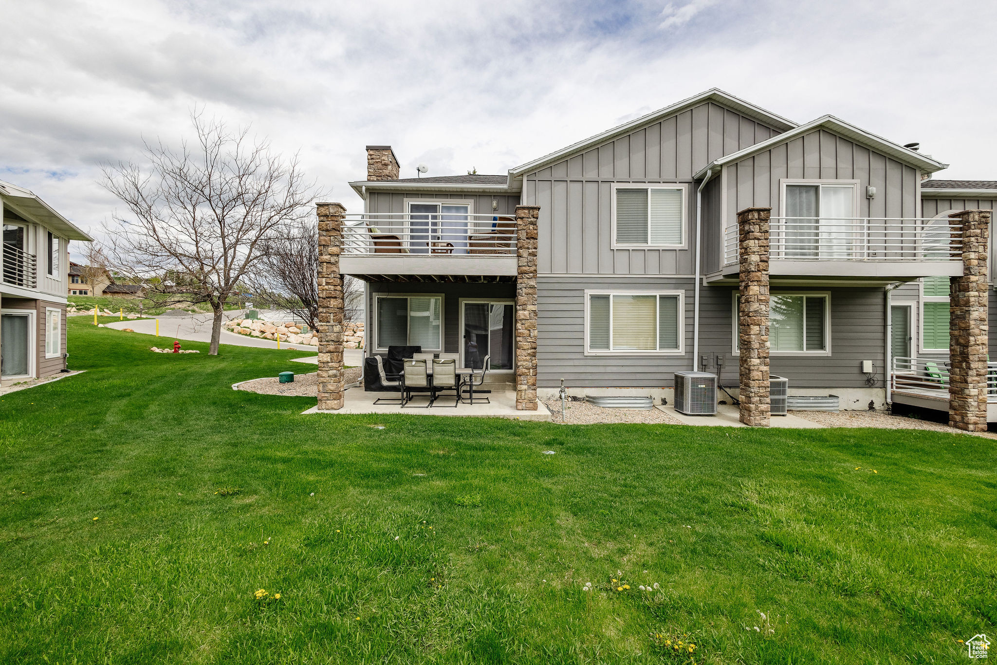 Back of house featuring a patio, central air condition unit, a balcony, and a yard