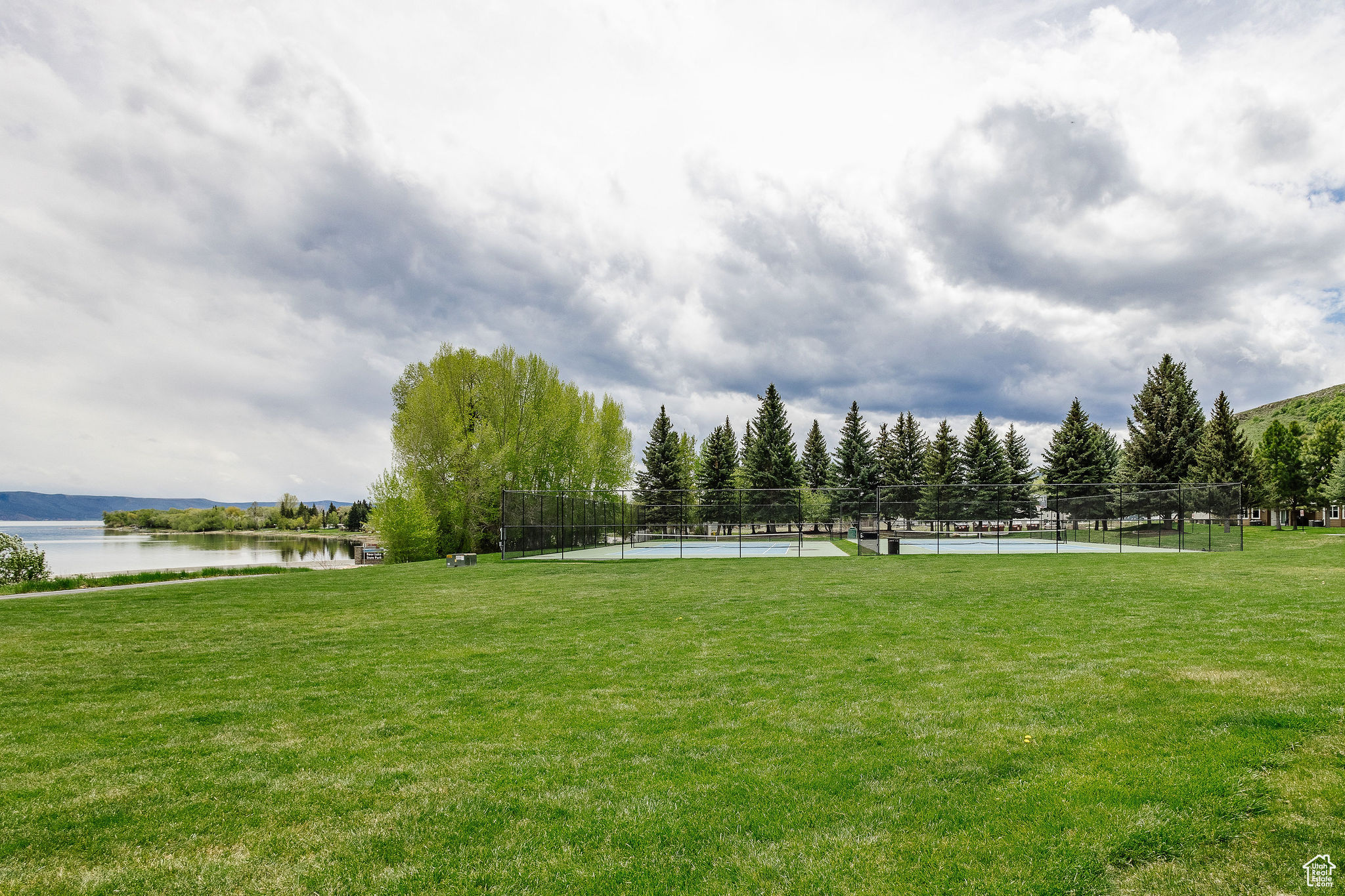 Surrounding community featuring a yard, a water view, and tennis court