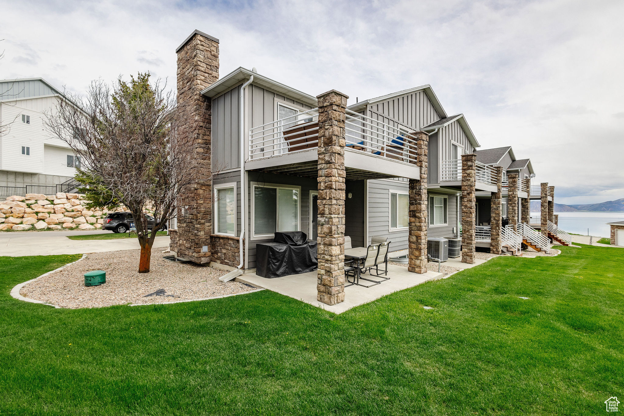 Back of house featuring a lawn, central AC unit, a water view, and a patio