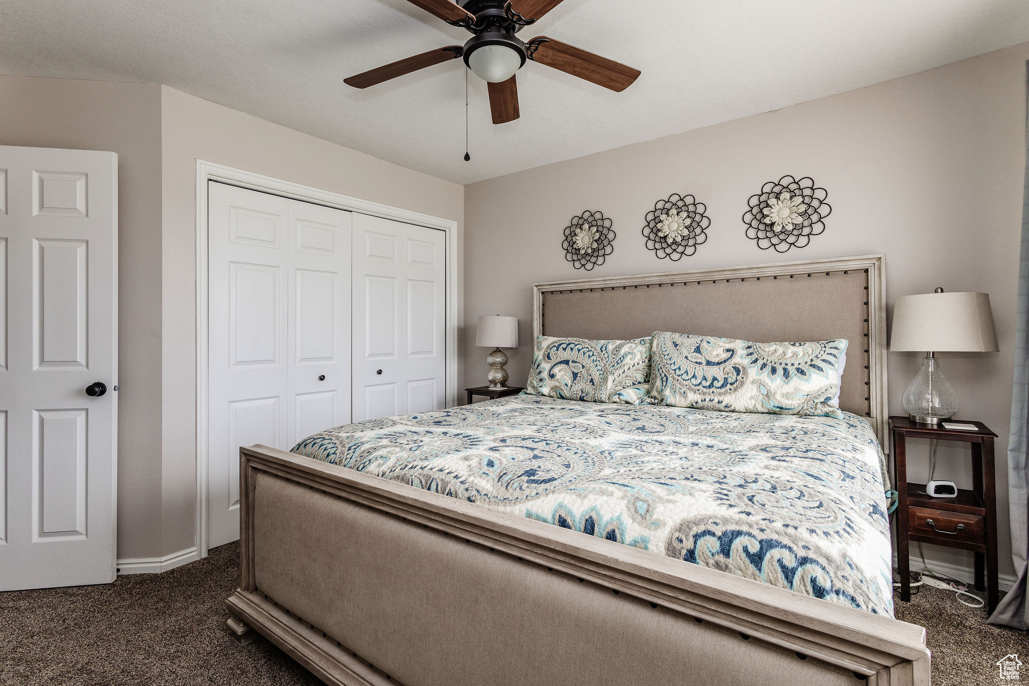 Carpeted bedroom featuring ceiling fan and a closet