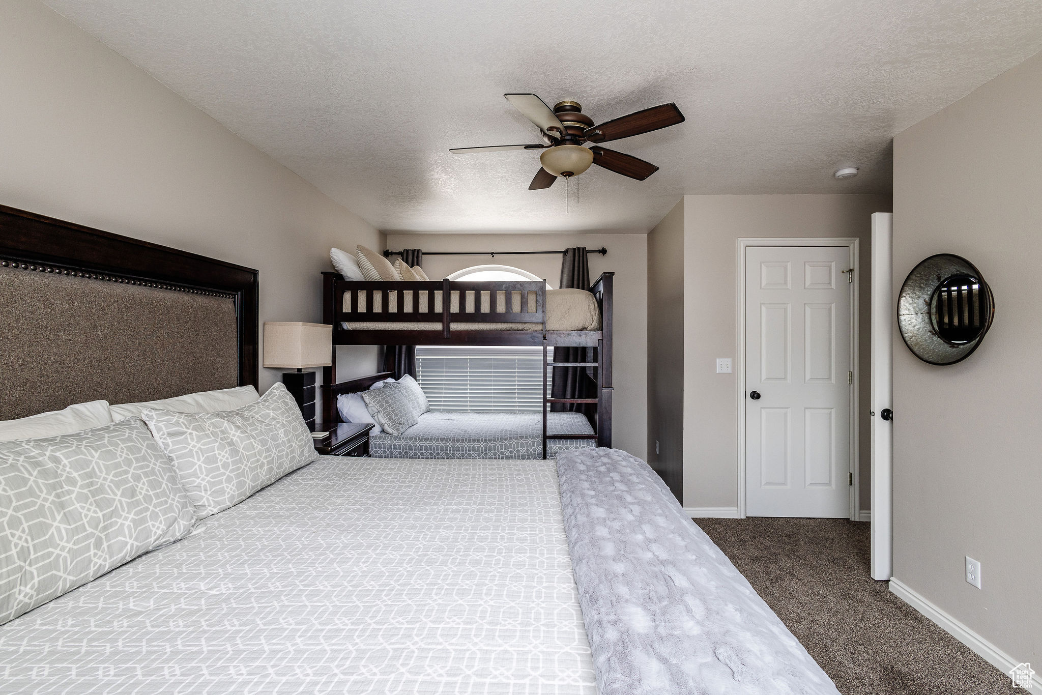 Bedroom featuring a textured ceiling, dark colored carpet, and ceiling fan