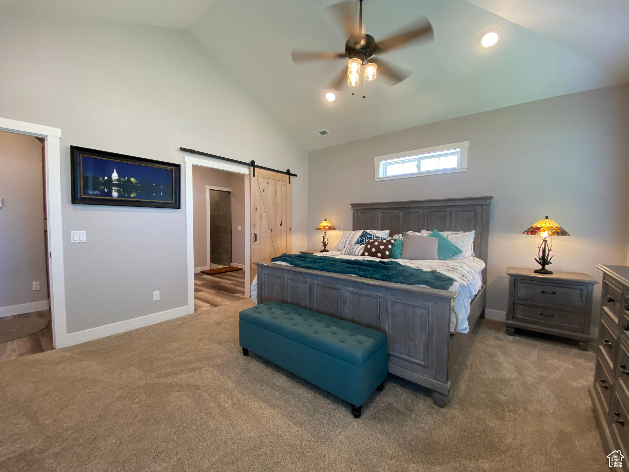 Bedroom featuring high vaulted ceiling, dark carpet, a barn door, and ceiling fan