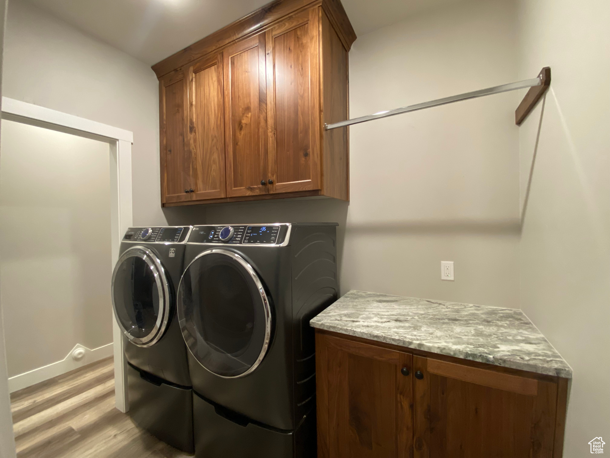 Clothes washing area with cabinets, light hardwood / wood-style flooring, and independent washer and dryer