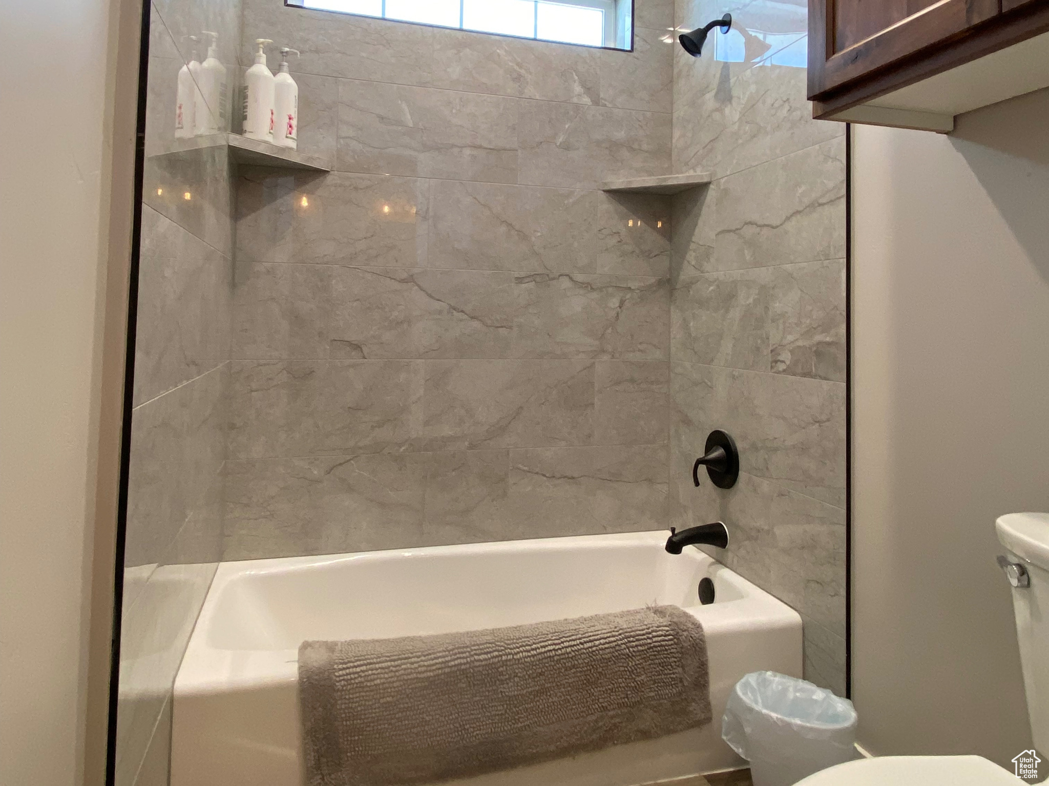 Bathroom featuring hardwood / wood-style floors, toilet, and tiled shower / bath combo