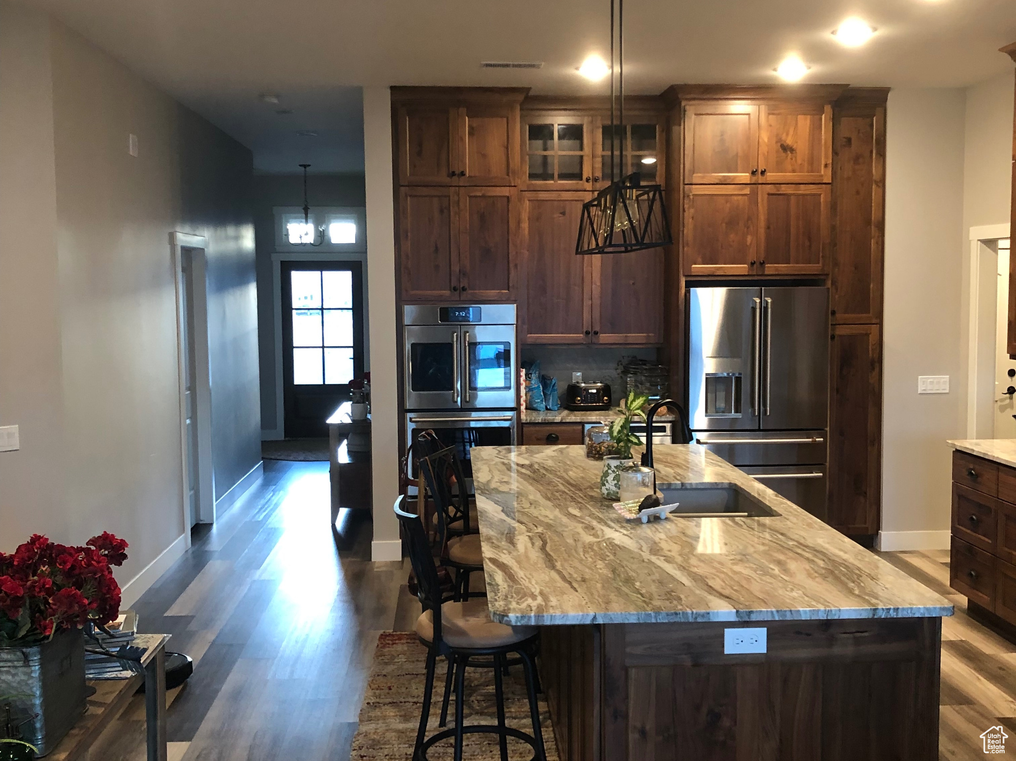 Kitchen featuring dark wood-type flooring, a kitchen island, appliances with stainless steel finishes, pendant lighting, and sink